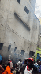 Crowds gather on busy Nairobi street near weathered building