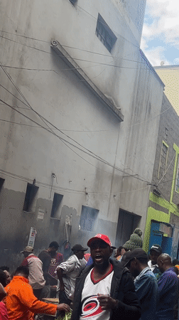 Crowds gather on busy Nairobi street near weathered building