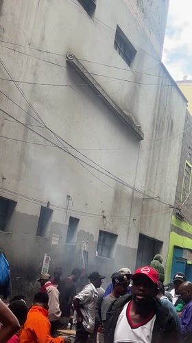 Crowds gather on busy Nairobi street near weathered building