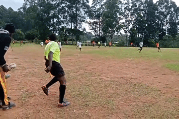 Soccer match underway in Turbo, Kenya with orange, white teams