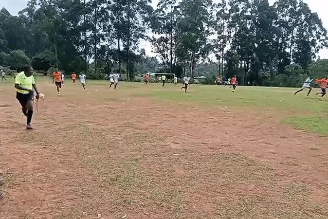 Soccer match underway in Turbo, Kenya with orange, white teams