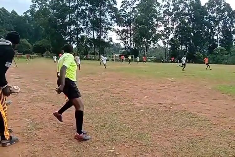 Soccer match underway in Turbo, Kenya with orange, white teams