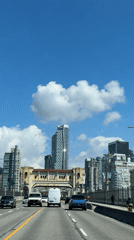 Vehicles cross bridge toward Vancouver skyline in daylight