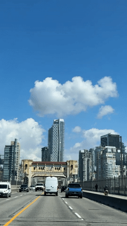 Vehicles cross bridge toward Vancouver skyline in daylight