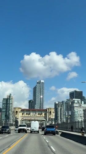 Vehicles cross bridge toward Vancouver skyline in daylight