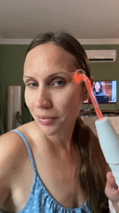 Woman uses glowing facial beauty device in Fethiye home