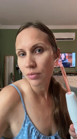 Woman uses glowing facial beauty device in Fethiye home