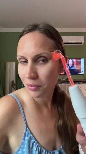 Woman uses glowing facial beauty device in Fethiye home