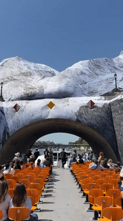 Orange-seated tour boat passes decorated bridge in Paris