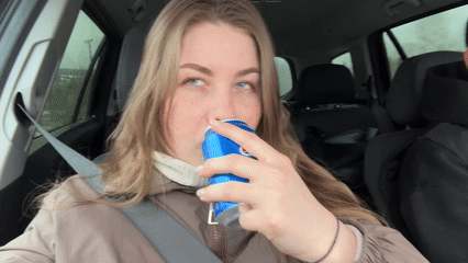 Woman drinks from can while sitting in car in Russia