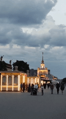 Evening visitors document VDNKh aerospace exhibits and illuminated pavilions