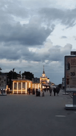 Evening visitors document VDNKh aerospace exhibits and illuminated pavilions