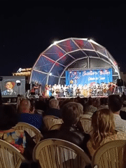 Evening outdoor concert with tent stage and gathering crowds