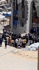 Outdoor prayer and crowds gather near a destroyed mosque in Khan Yunis
