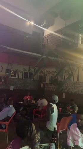 Man dances at bar while patrons socialize in Ado