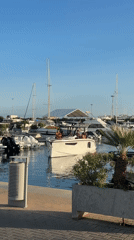 Ibiza marina: motorboat on the water, anchor sculpture on shore