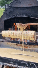 Pouring batter onto a rotating spit over open fire