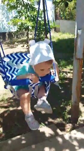 Child plays in backyard garden swing in Tavaksay