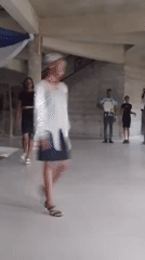 Two women practice walking routines in large concrete room