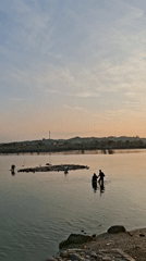 Residents gather along Lhokseumawe waterway during golden hour