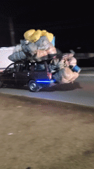 Overloaded cargo vehicles navigate nighttime streets in Bukuru, Nigeria