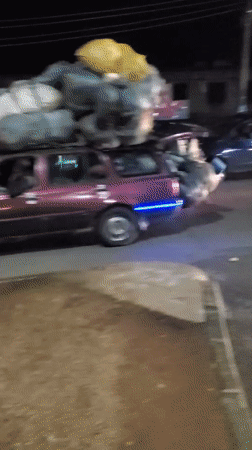 Overloaded cargo vehicles navigate nighttime streets in Bukuru, Nigeria