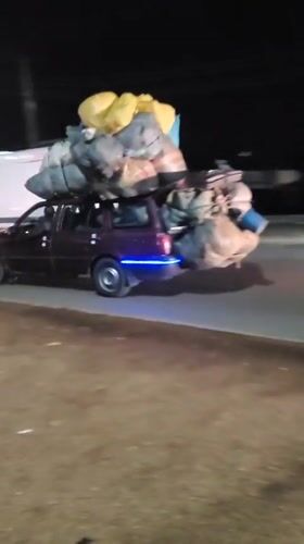 Overloaded cargo vehicles navigate nighttime streets in Bukuru, Nigeria