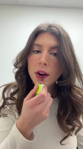 Woman applies lip gloss in Longueuil