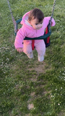Baby in pink outfit swings peacefully in Elena park