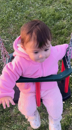 Baby in pink outfit swings peacefully in Elena park