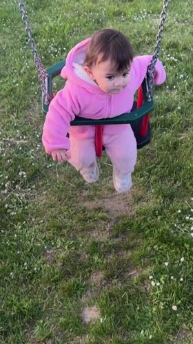 Baby in pink outfit swings peacefully in Elena park