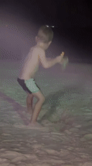 Child digs in sand on dimly lit Koh Phangan beach
