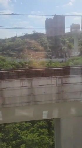 Train passenger films scenic bridge and hillside views in China