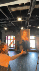 Person reaches for hanging portrait in stained glass room