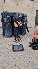 Street musician performs near sculpture in Durham dining area
