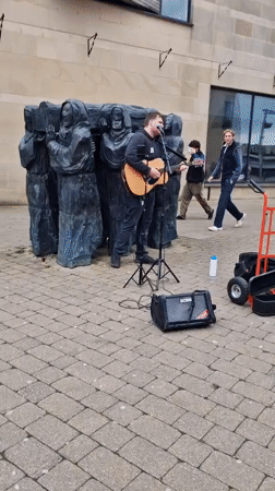 Street musician performs near sculpture in Durham dining area