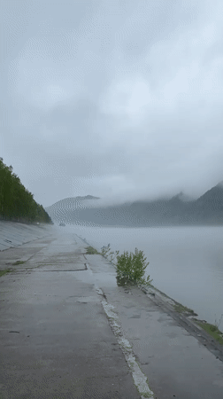 Vehicle parked beside water in foggy Divnogorsk morning