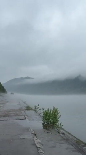 Vehicle parked beside water in foggy Divnogorsk morning
