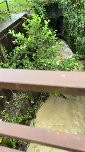 Heavy rain, rushing channels, and wet roads on a stormy afternoon