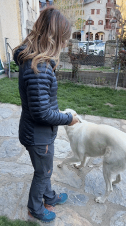 Woman interacts with white dog on stone patio in Benasque