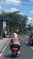 Two people ride scooter through North Kuta streets