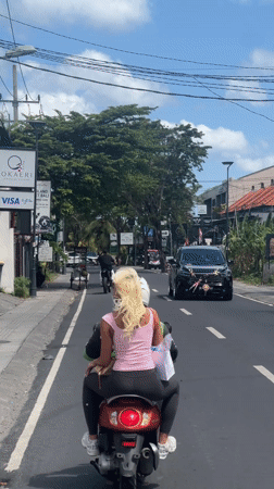 Two people ride scooter through North Kuta streets