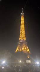 Eiffel Tower glowing at night, crowd taking it all in