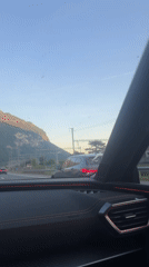 Vehicle travels Swiss highway near mountains, parallel train tracks
