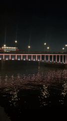 Pink-lit Thames bridge and city skyline after dark