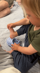 Child puts on shoes in Bat Yam bedroom