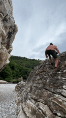 Man climbs coastal rocks in Montenegro under overcast skies