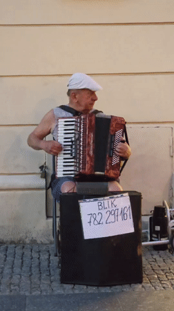 Accordion player busking on a Warsaw street, BLIK payments accepted