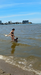 Woman plays fetch with dog at Anapa beach Sunday morning