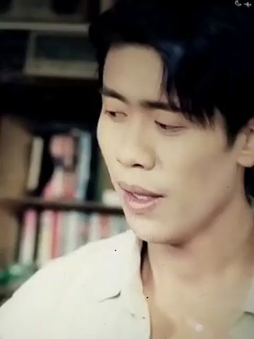 This media file is a short video clip featuring two separate scenes, each focusing on a close-up of a young East Asian man. The first scene shows a man with dark hair, wearing a light-colored, collared shirt. He appears to be speaking, with his mouth slightly open. His eyes are partially closed, suggesting a thoughtful or emotional moment. The background is blurred, but appears to be a bookshelf filled with books, hinting at an indoor setting, possibly a study or library.

The second scene features a different young man, also with dark hair, but with a more uniform haircut. He is wearing a dark green, collared garment, resembling a military uniform or work attire, with a strap visible across his shoulder. Like the first man, he is also speaking, with his mouth open, and his eyes are closed in the initial frames before opening. The background again appears to be a room with bookshelves, suggesting a similar indoor setting. The lighting in both scenes is soft, and there are no indications of time of day or weather. The overall mood of both clips is introspective and focused on the expressions of the individuals. No text is visible in the media file.